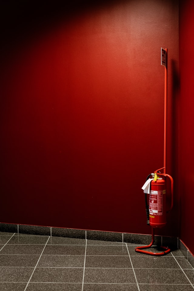 Extintor rojo sobre pared roja